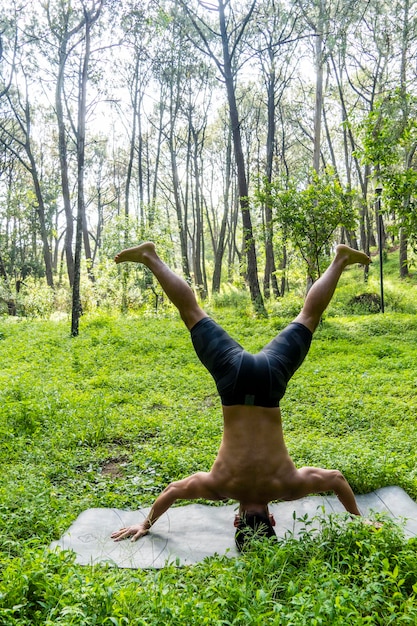 Uomo latinoamericano che fa yoga postura yoga postura Bee indietro Prsthatah Brahmara foresta