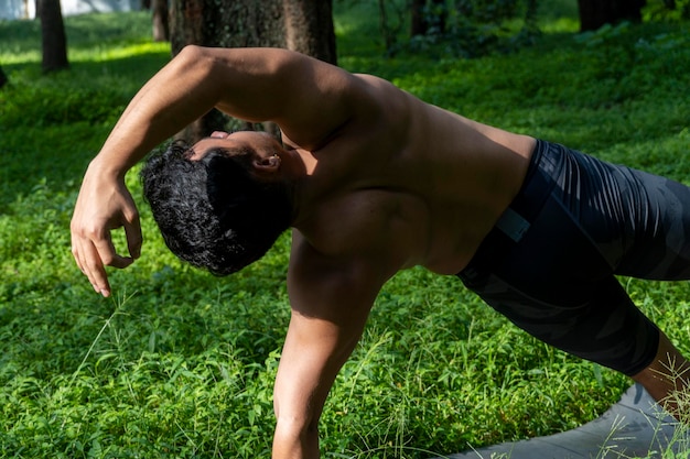 Uomo latinoamericano che fa yoga postura yoga postura Bee indietro Prsthatah Brahmara foresta