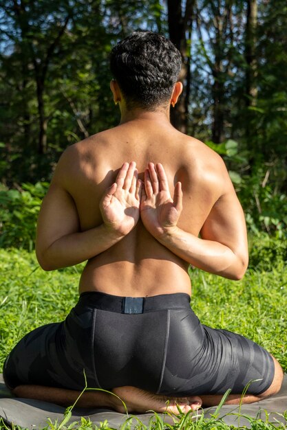 Uomo latinoamericano che fa yoga postura yoga postura Bee indietro Prsthatah Brahmara foresta