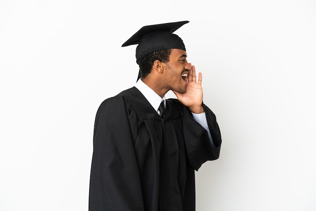 Uomo laureato afroamericano sopra fondo bianco isolato che grida con la bocca spalancata al lateral