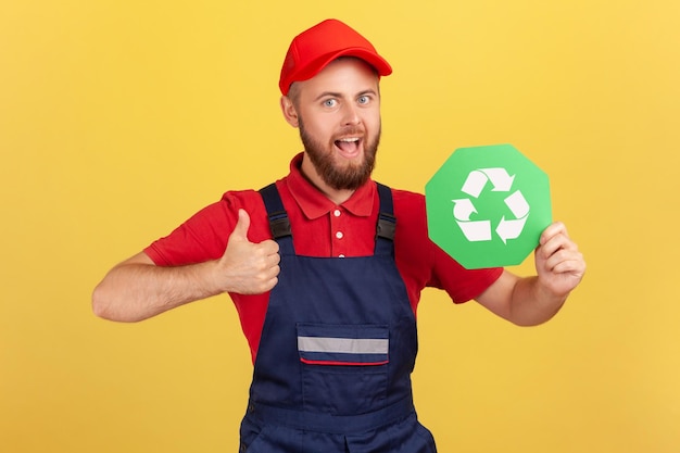 Uomo lavoratore in piedi e con segno di riciclaggio pensando verde mostrando pollice in su