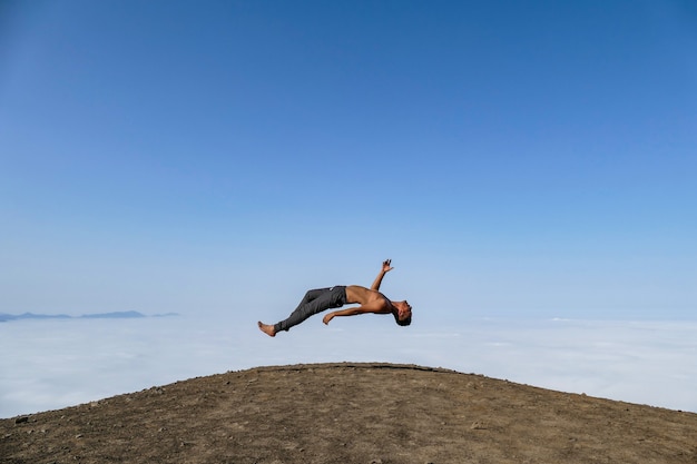 uomo levitante su una collina cielo blu e nuvole sullo sfondo