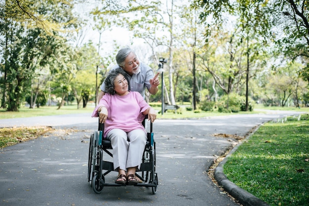 Uomo maggiore che si occupa della moglie disabile nella sua sedia a rotelle.