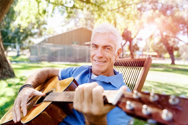 Uomo maggiore che suona la chitarra all'aperto