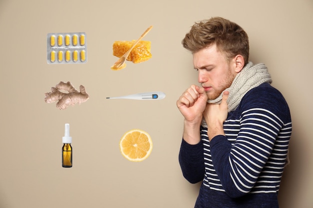 Uomo malato circondato da diversi farmaci e prodotti per il trattamento delle malattie su sfondo beige