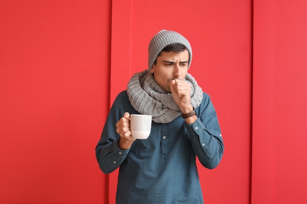 Uomo malato con tè caldo sulla superficie del colore