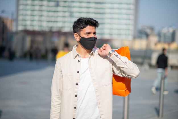 Uomo mascherato che trasporta borse della spesa mentre indossa una maschera covid e concetto di coronavirus