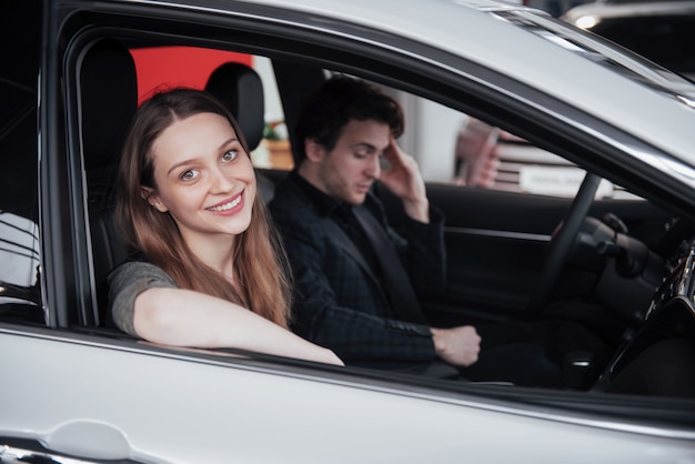 Uomo maturo bello che sorride a sua moglie mentre sedendosi insieme nella loro nuova automobile