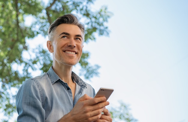 Uomo maturo bello utilizzando il telefono cellulare, acquisti online