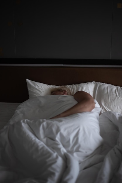 Uomo maturo che dorme nel suo letto con lenzuola bianche Buon riposo e sonno salutare durante la notte