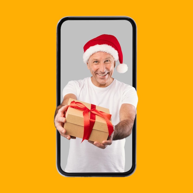 Uomo maturo che fa il regalo di Natale che esce dallo schermo della cella