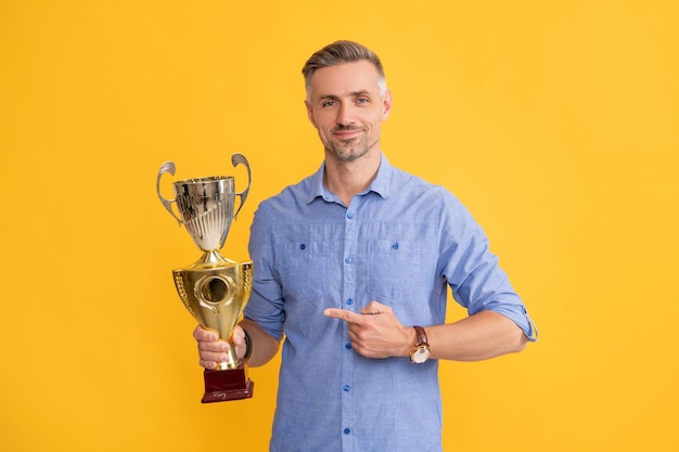 Uomo maturo che punta il dito coppa d'oro premio motivazione del successo aziendale