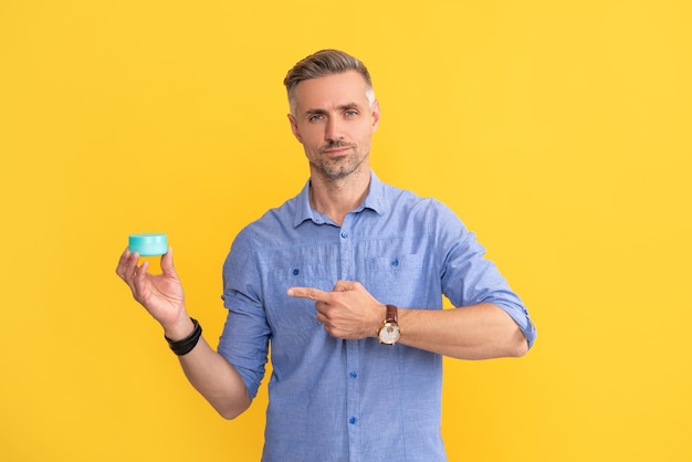 Uomo maturo che punta il dito sul ragazzo crema viso tenere maschera per capelli o crema per la pelle