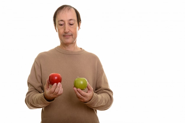 uomo maturo che sceglie fra la mela rossa e verde