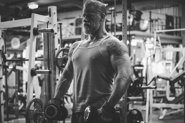 Uomo maturo che si esercita con i manubri in palestra