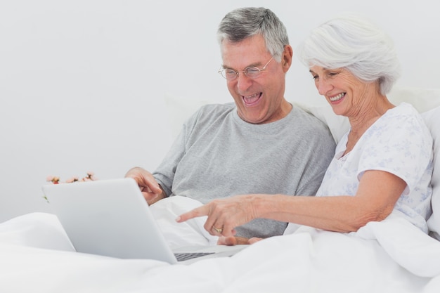 Uomo maturo con moglie che punta a un computer portatile