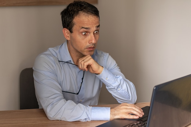 Uomo maturo con occhi sporgenti guardando il suo laptop