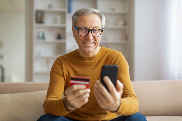 Uomo maturo con telefono e carta di credito.