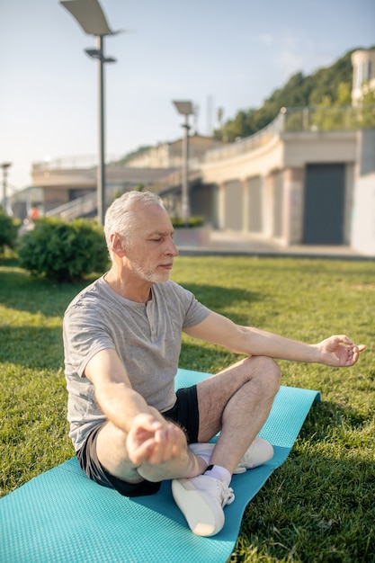 Uomo maturo dai capelli grigi che medita con le mani in Gyan mudra