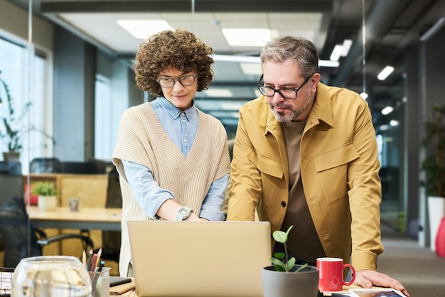 Uomo maturo e giovane imprenditrice che guardano webinar online