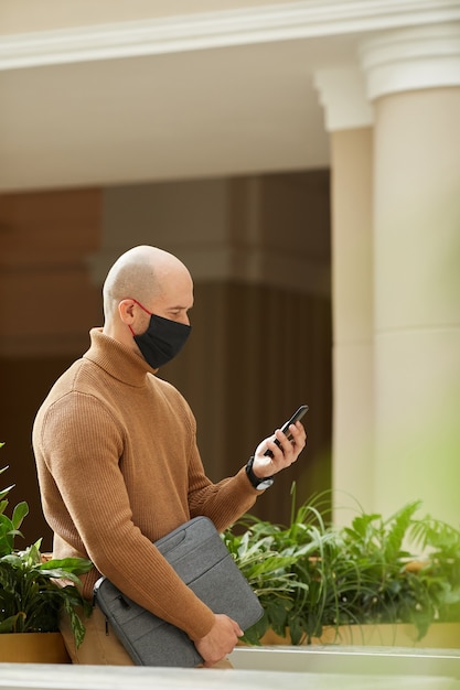 Uomo maturo in maschera utilizzando il suo telefono cellulare