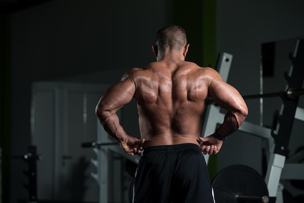 Uomo maturo sano in piedi forte in palestra e flettendo i muscoli Bodybuilder atletico muscolare Fitness maschile in posa dopo gli esercizi