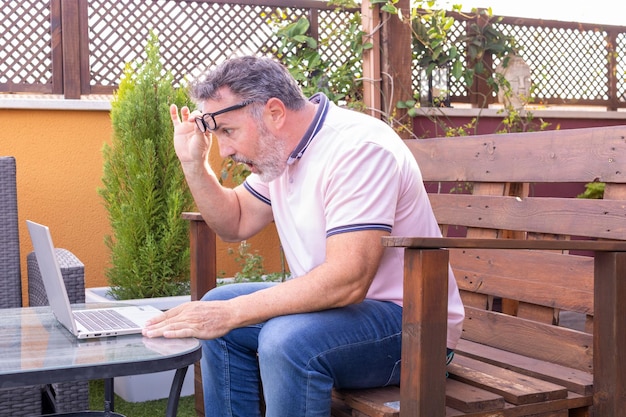 Uomo maturo scioccato che esamina il computer portatile