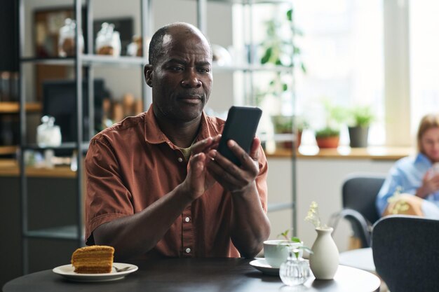 Uomo maturo serio con sms sul cellulare o guardando attraverso le notizie online