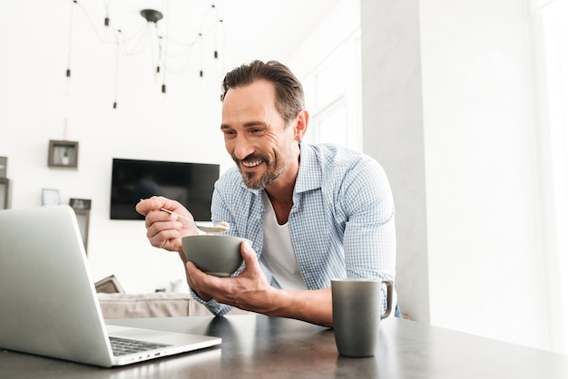Uomo maturo sorridente che mangia prima colazione sana