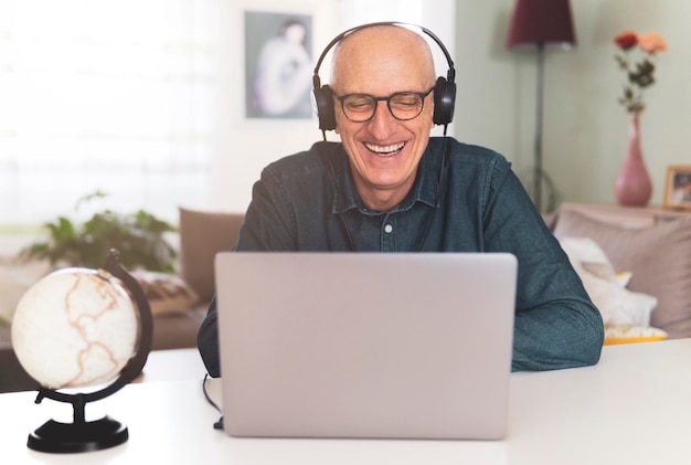Uomo maturo sorridente che usa il portatile a casa