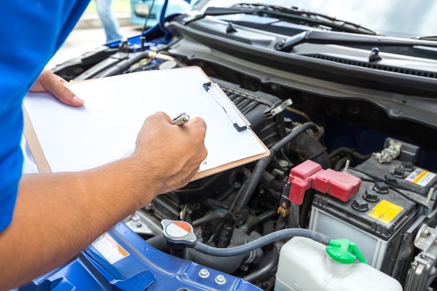 Uomo meccanico che tiene appunti e controlla l'auto