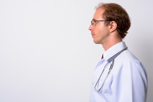 uomo medico con i capelli biondi che indossa occhiali da vista contro il muro bianco