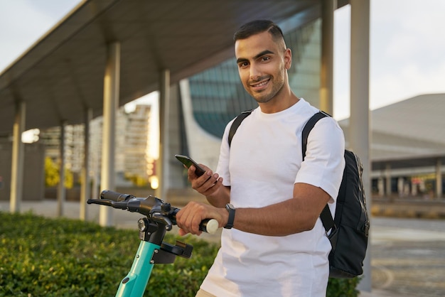 Uomo mediorientale che sblocca lo scooter elettrico mentre si prepara alla corsa