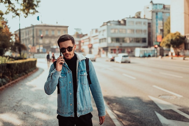 Uomo moderno in occhiali da sole che parla sullo smartphone per strada.