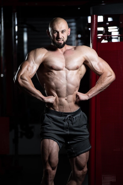 Uomo muscolare bello che flette i muscoli in palestra