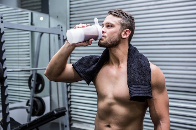 Uomo muscolare che beve cocktail di proteine