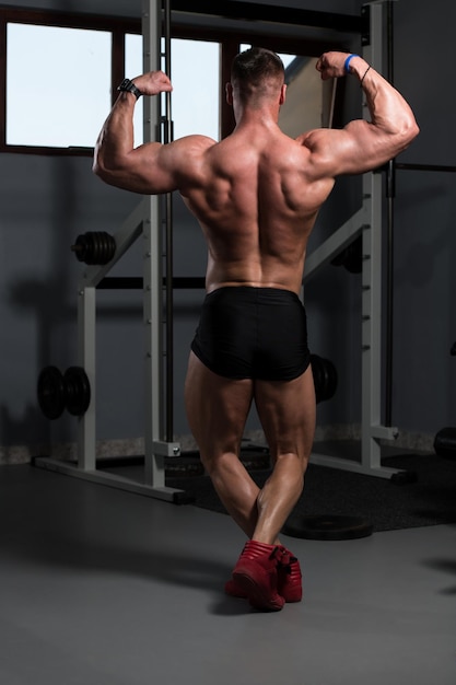 Uomo muscolare che flette i muscoli in palestra