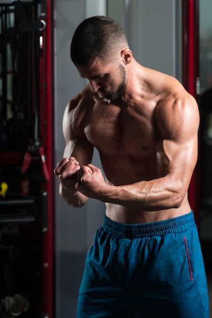 Uomo muscolare che flette i muscoli in palestra