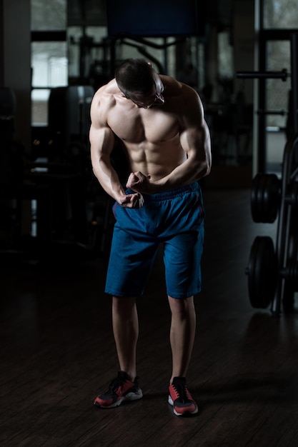 Uomo muscolare che flette i muscoli in palestra