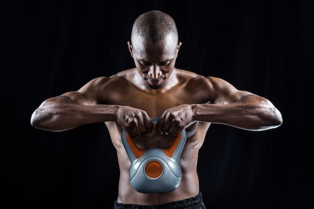 Uomo muscolare che osserva giù mentre si esercita con kettlebell