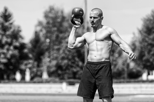 Uomo muscolare che si esercita con il kettlebell all'aperto