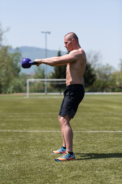 Uomo muscolare che si esercita con il kettlebell all'aperto