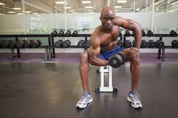 Uomo muscolare che si esercita con la testa di legno in palestra