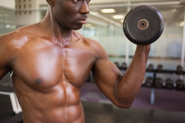 Uomo muscolare che si esercita con la testa di legno in palestra