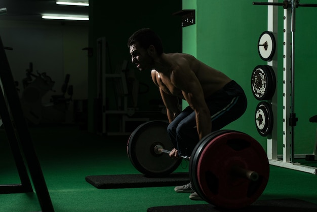 Uomo muscolare che solleva l'ascensore morto in palestra