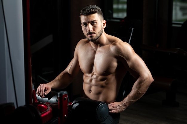 Uomo muscolare dopo l'esercizio che riposa in palestra