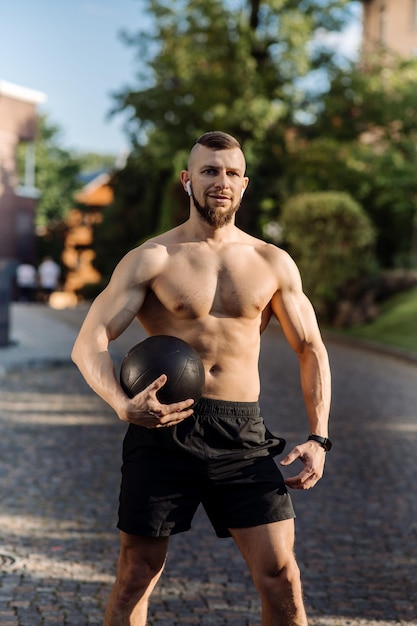 Uomo muscolare o allenatore di fitness con palla fitness all'aperto