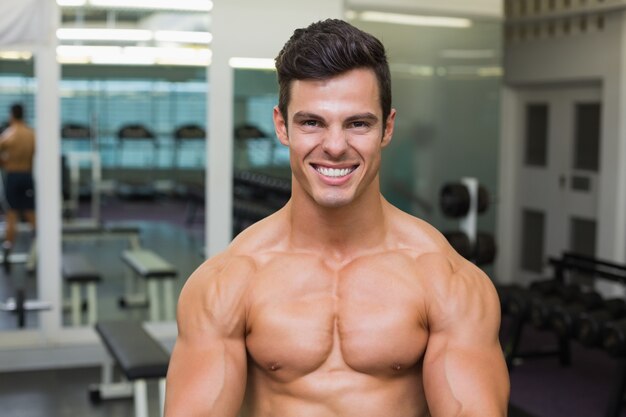 Uomo muscolare senza camicia sorridente in palestra