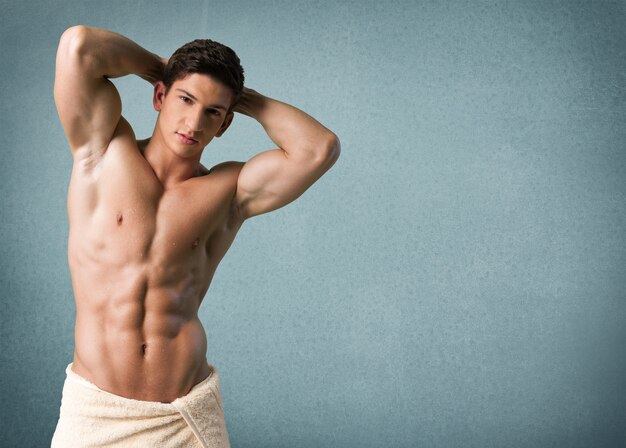 Uomo muscoloso bagnato avvolto in un asciugamano isolato su bianco