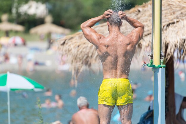 Uomo muscoloso bello fa una doccia all'aperto